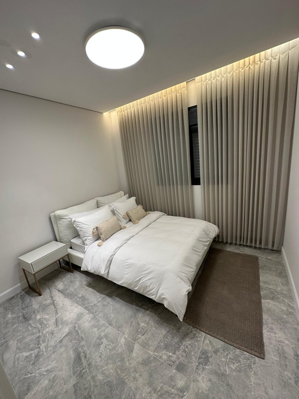 A finished bedroom with a cove-lit ceiling, smooth walls and clean trim