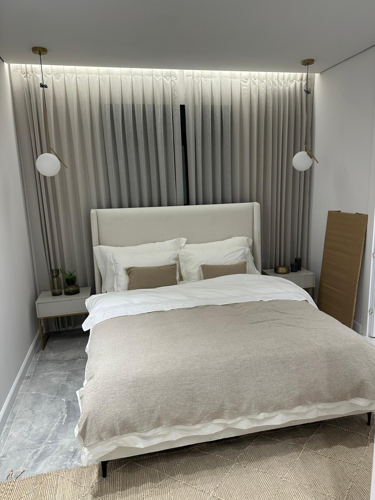 A finished basement bedroom with floor-to-ceiling drapery, cove lighting, and pendant lights